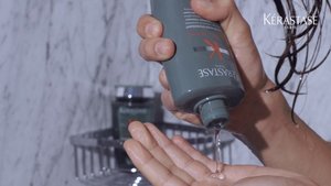 Homem a colocar na palma da mão o shampoo da gama Genesis Homme da Kérastase