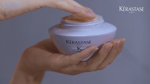 Mulher a retirar um pouco de máscara da gama Symbiose da Kérastase para aplicar no cabelo