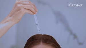 Mulher a aplicar no couro cabeludo o sérum noturno anti-caspa da gama Symbiose da Kérastase