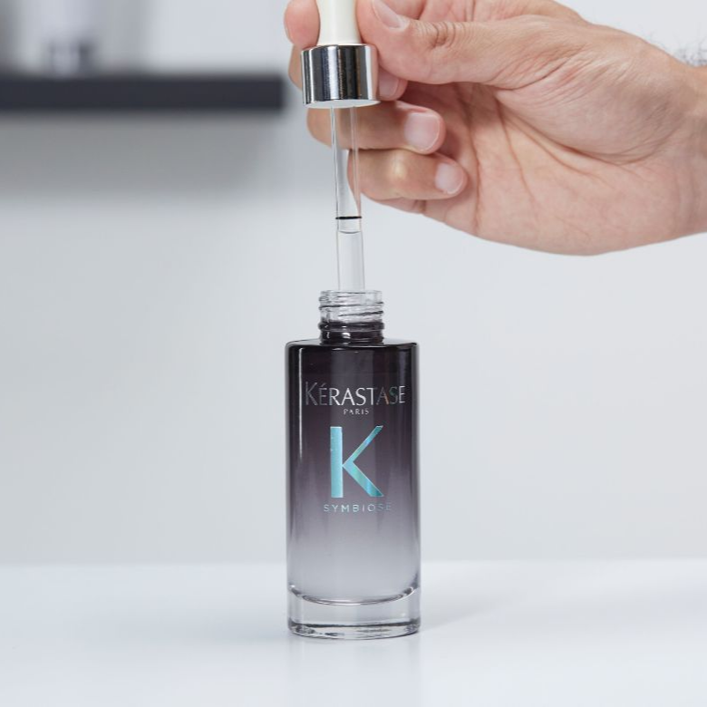 Mulher a retirar uma dose do sérum noturno da gama symbiose da kérastase