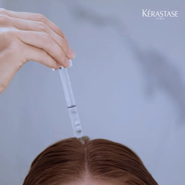 Mulher a aplicar no couro cabeludo o sérum symbiose da kérastase